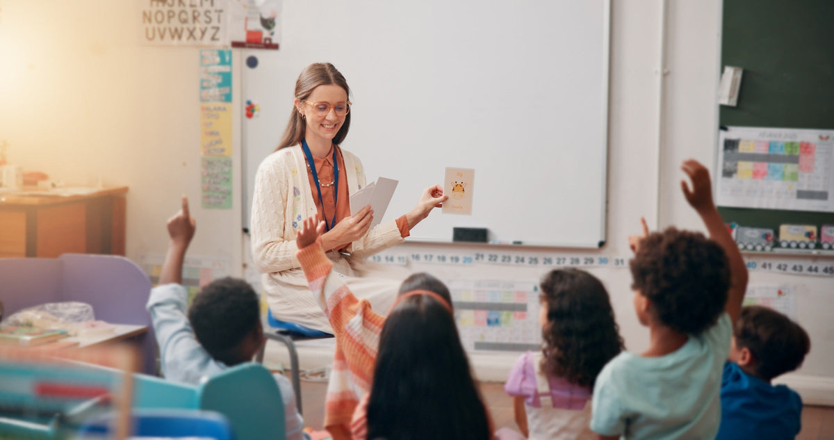 Teacher leading a classroom activity with children raising their hands.
