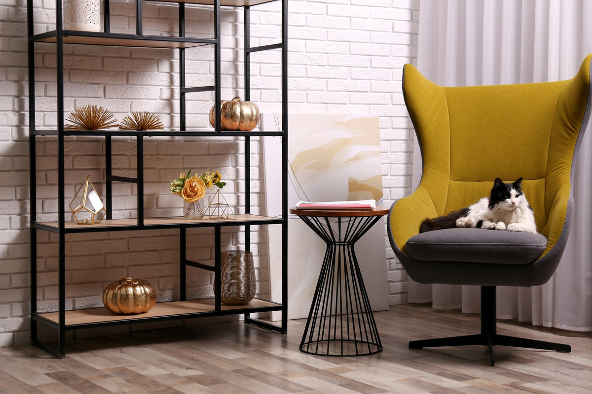 Black-and-white cat resting on a yellow armchair in a living room.