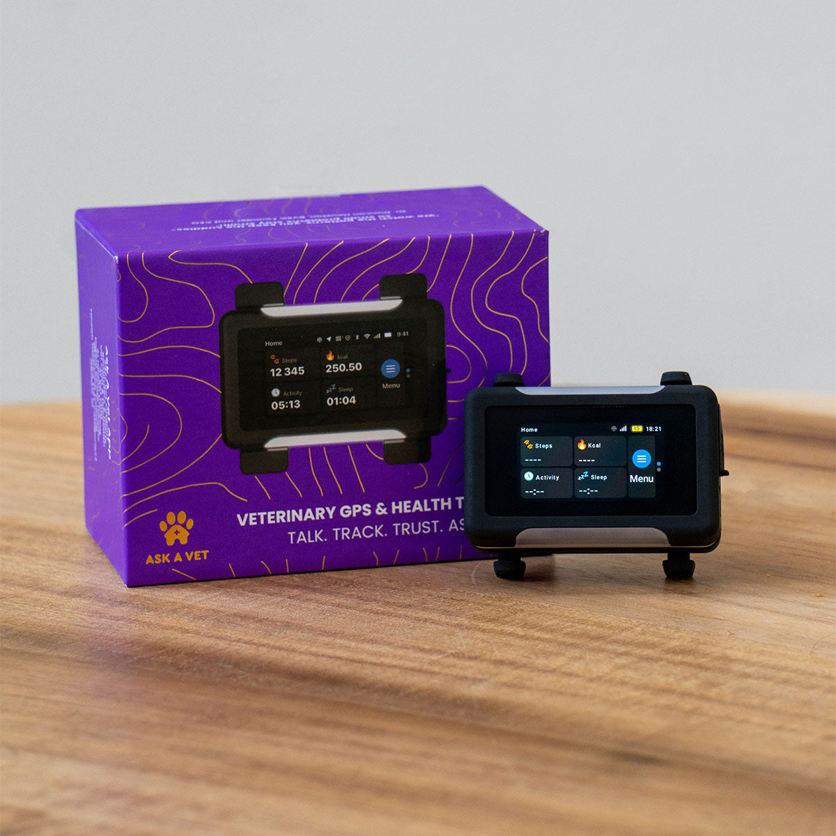 Black / Gold | Smart GPS & Health Tracker: The Black / Gold tracker beside its purple box on a wooden table