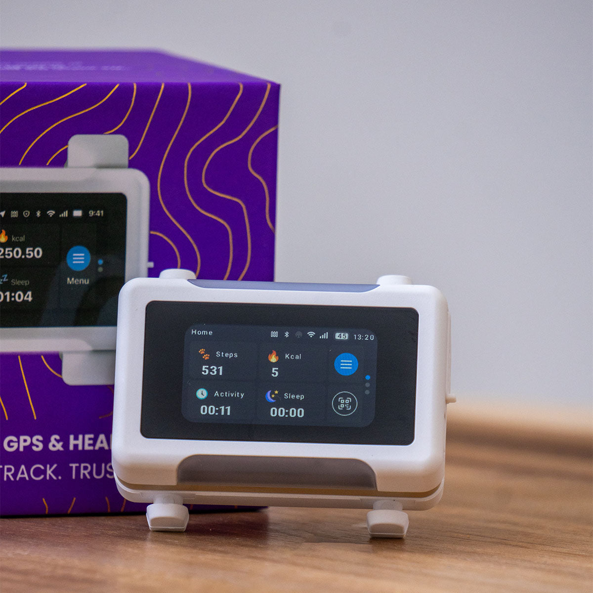 White / Gold | Smart GPS & Health Tracker: Close-up of the White / Gold tracker in front of its purple box